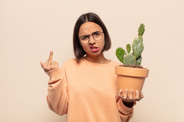 Mujer latina joven que se siente enojada, molesta, rebelde y agresiva, moviendo el dedo medio, contraatacando