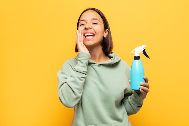 Mujer latina joven que se siente feliz, emocionada y positiva, dando un gran grito con las manos al lado de la boca, gritando