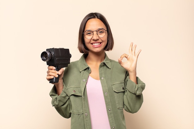 Mujer latina joven que se siente feliz, relajada y satisfecha, mostrando aprobación con gesto bien, sonriendo