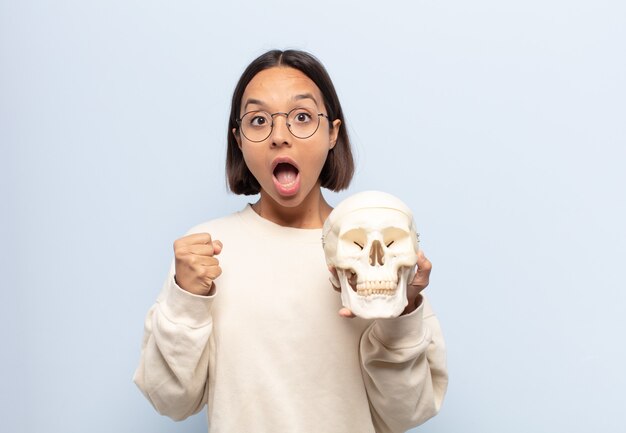 Mujer latina joven que se siente sorprendida, emocionada y feliz, riendo y celebrando el éxito, diciendo ¡guau!