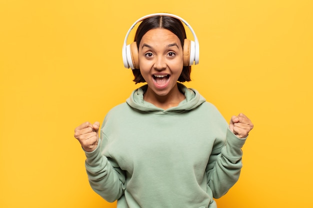 Mujer latina joven que se siente sorprendida, emocionada y feliz, riendo y celebrando el éxito, diciendo ¡guau!