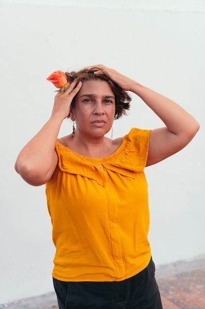 Mujer latina madura con flor de naranja en la calle urbana