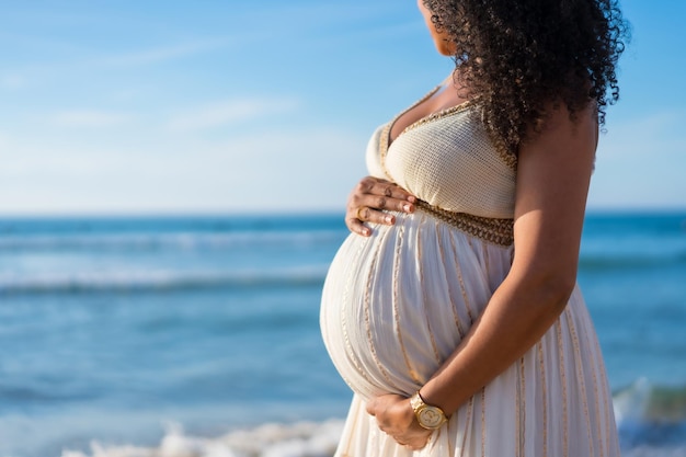 Mujer latina de maternidad embarazada en la playa al atardecer concepto de maternidad