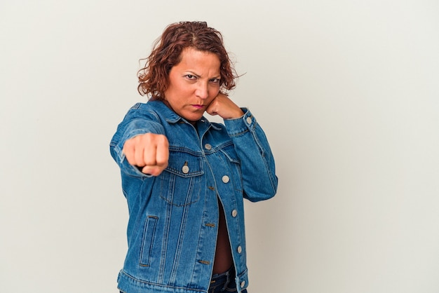 Mujer latina de mediana edad aislada sobre fondo blanco lanzando un puñetazo, ira, luchando debido a una discusión, boxeo.