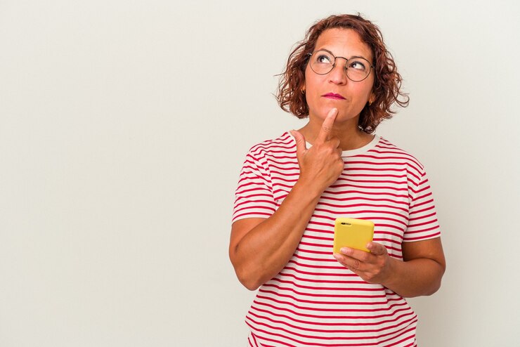 Foto mujer latina de mediana edad aislada sobre fondo blanco mirando hacia los lados con expresión dudosa y escéptica.