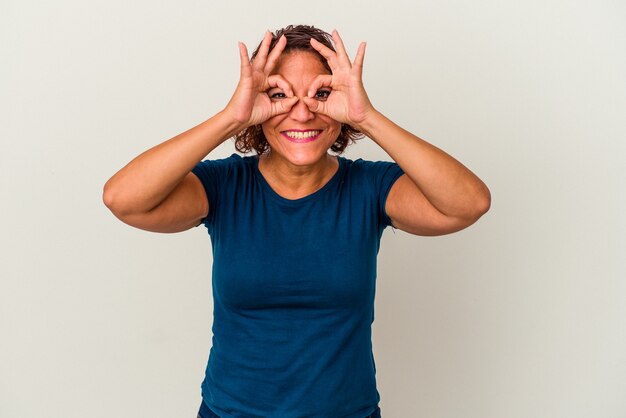 Mujer latina de mediana edad aislada sobre fondo blanco mostrando bien firmar sobre los ojos