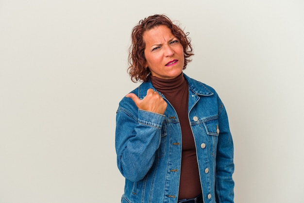 Mujer latina de mediana edad aislada sobre fondo blanco sorprendido apuntando con los dedos índices a un espacio de copia.