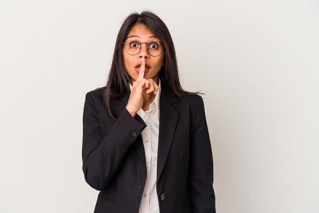 Mujer latina de negocios joven aislada sobre fondo blanco manteniendo un secreto o pidiendo silencio.