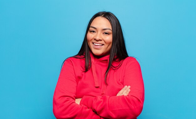 Mujer latina que parece un triunfador feliz, orgulloso y satisfecho sonriendo con los brazos cruzados