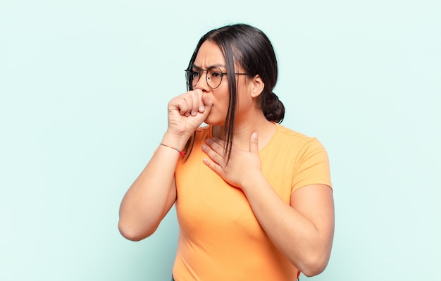 Mujer latina que se siente enferma con dolor de garganta y síntomas de gripe, tos con la boca cubierta