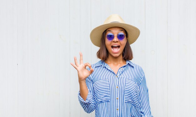 Mujer latina que se siente exitosa y satisfecha, sonriendo con la boca abierta, haciendo un buen signo con la mano