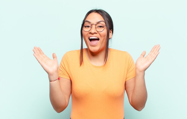 Mujer latina que se siente feliz, emocionada, sorprendida o conmocionada, sonriendo y asombrada por algo increíble