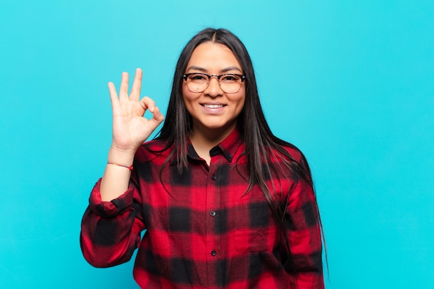 Mujer latina que se siente feliz, relajada y satisfecha, mostrando aprobación con gesto bien, sonriendo