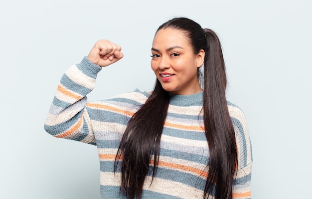 Mujer latina que se siente feliz, satisfecha y poderosa, flexionando el ajuste y bíceps musculosos, luciendo fuerte después del gimnasio