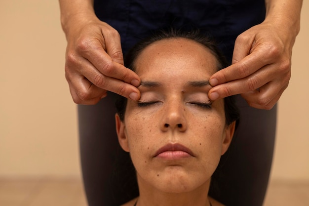 Mujer latina recibiendo un masaje ayurvédico en la cara con puntos de presión específicos