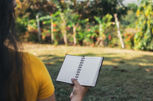 mujer latina sentada en el campo leyendo su cuaderno