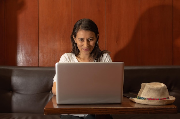 Mujer latina sentada en una vieja cafetería trabajando en su laptop