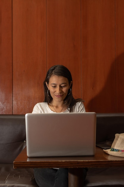 Mujer latina sentada en una vieja cafetería trabajando en su laptop