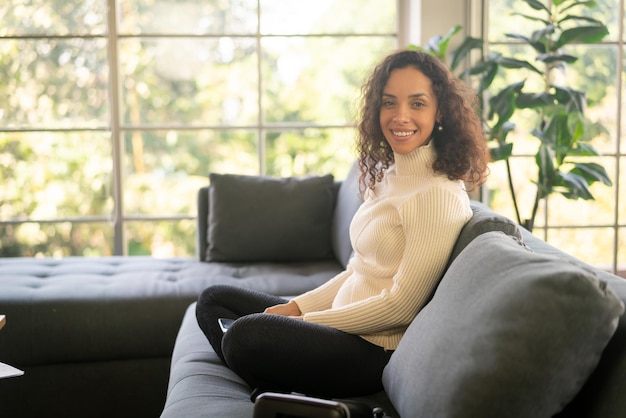 Mujer latina sonriendo y sentada en el sofá