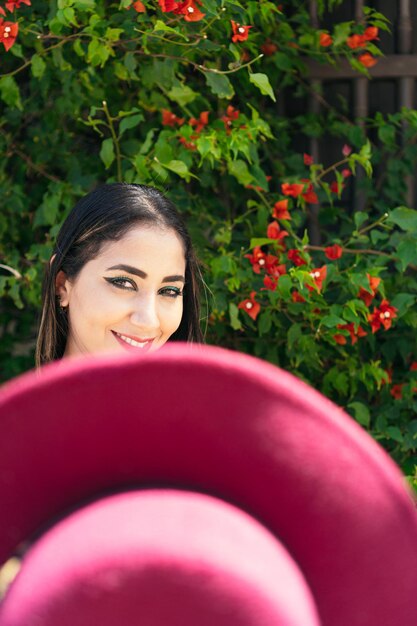 Mujer latina tomando un retrato selfie con sombrero en la calle - Un chico feliz sonriendo a la cámara.