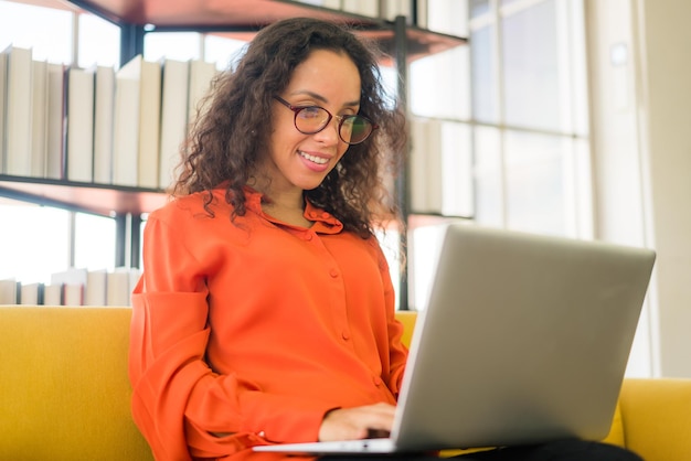 mujer latina trabajando con una laptop en un sofá en casa