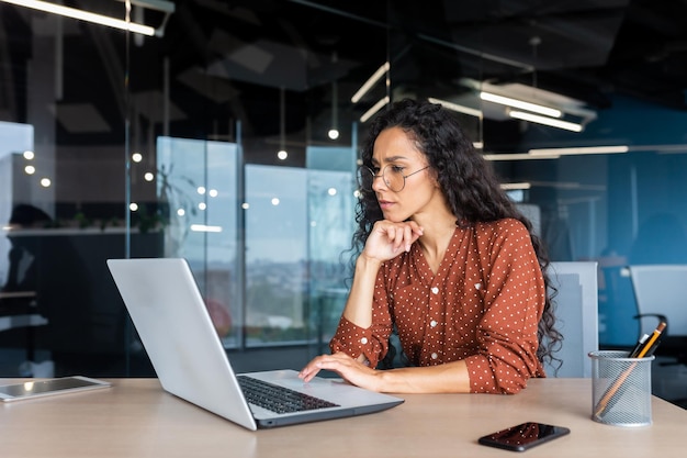 Mujer latinoamericana de pensamiento serio que trabaja dentro de la oficina empresaria reflexionando complejo