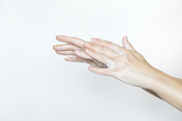 mujer se lava las manos con jabón sobre un fondo blanco