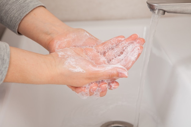 La mujer se lava las manos con jabón sobre el lavabo. Prevención y protección de la salud.