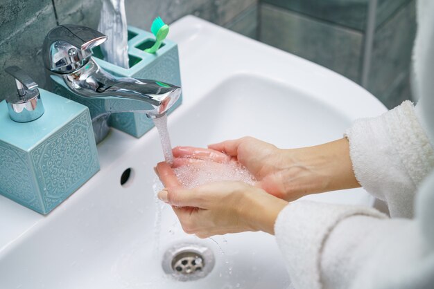 Mujer lava su mano en el lavabo del baño