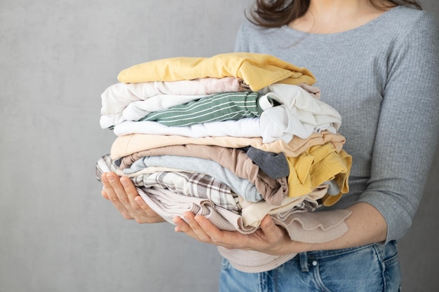 La mujer de la lavandería sostiene una pila de ropa en sus manos después de la limpieza en seco de las tareas domésticas de limpieza de planchado