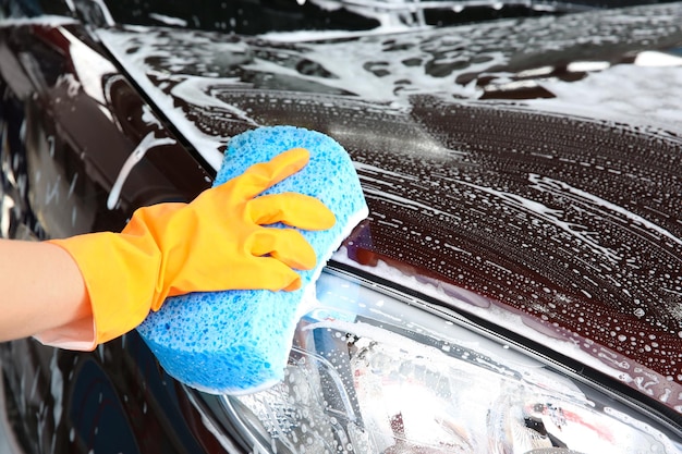 Mujer lavando coche con esponja primer plano