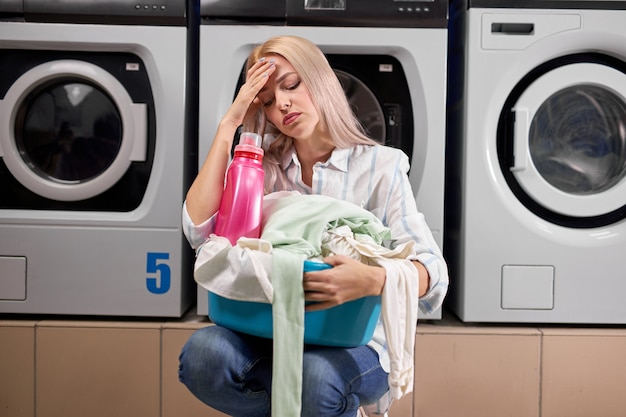 Mujer lavando ropa, con expresión triste y deprimida, con mal humor después de un duro día de trabajo, en la casa de lavado. personal cansado y agotado