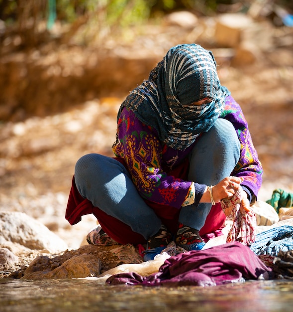 Mujer lavando ropa en el río del pintoresco Dades Gorge en las montañas del Atlas
