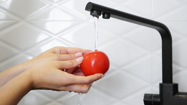 Mujer lavando tomates y tomate en sus manos cocina blanca