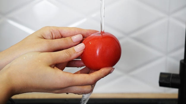 Mujer lavando tomates y tomate en sus manos