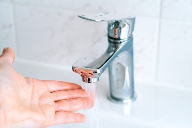 Mujer lavándose las manos con agua corriente