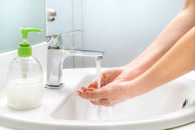 Mujer lavándose las manos con jabón en el fregadero para una buena higiene y limpieza
