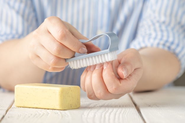 Mujer lavándose las manos con pastilla de jabón y cepillo de limpieza