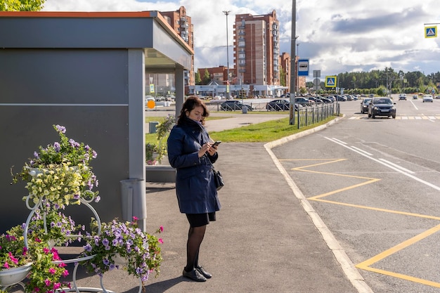 Mujer lee información en un teléfono móvil mientras espera el autobús