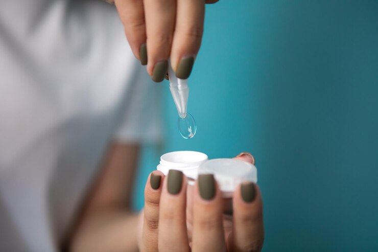 Mujer con lentes de contacto y pinzas sobre fondo azul, primer plano