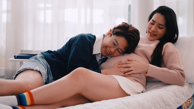 La mujer lesbiana asiática embarazada y su pareja están felices de pasar tiempo juntos en casa.