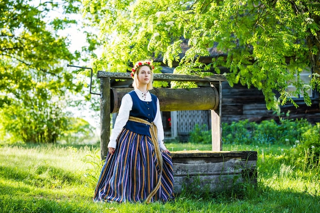 Mujer letona con ropa tradicional posando en el fondo de la naturaleza en el festival de la aldea Ligo Riga Letonia