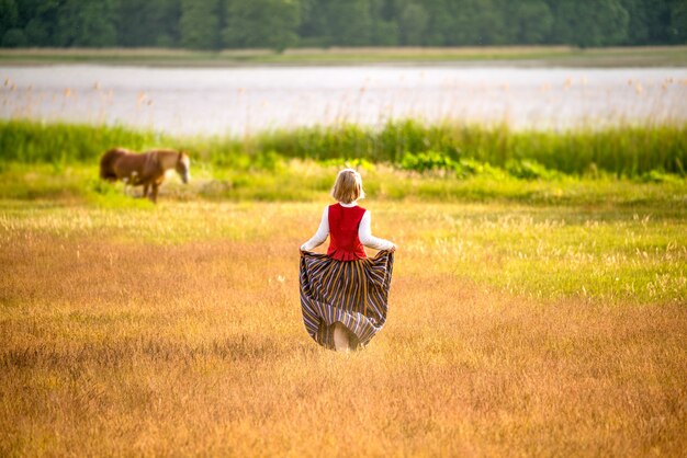 Mujer letona en vestimentas tradicionales en campo