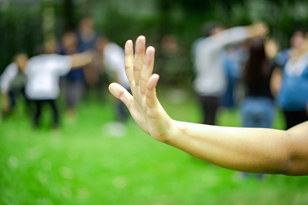La mujer levanta la mano y muestra cinco dedos de su mano en el jardín desenfoque de un montón de gente en segundo plano.