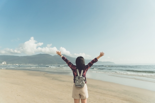 Mujer levanta las manos hasta el concepto de libertad del cielo con cielo azul y verano