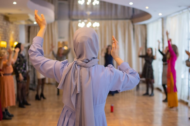 Foto mujer levantando las manos y bailando emocionada mujer joven celebrando una victoria mujer musulmana en trad...