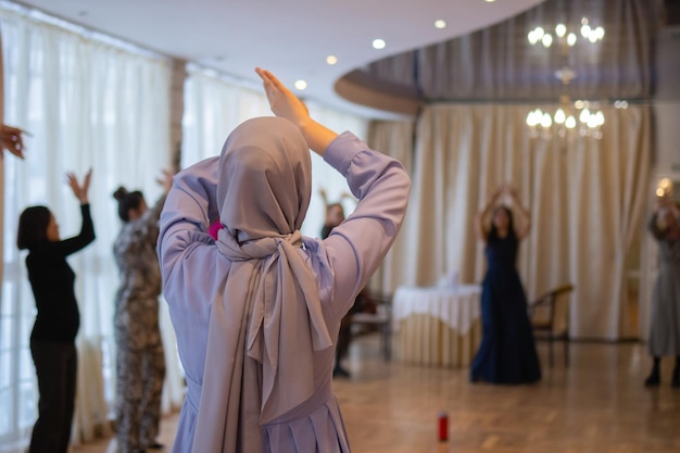 Mujer levantando las manos y bailando Mujer joven emocionada celebrando una victoria Mujer musulmana en ropa islámica tradicional hijab Concepto de celebración de Año Nuevo de cumpleaños