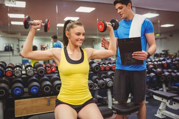 Mujer levantando pesas con su entrenador