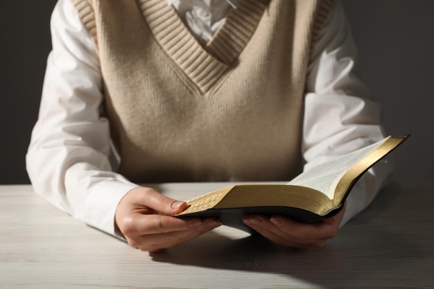 Mujer leyendo la Biblia en el primer plano de la mesa de madera blanca