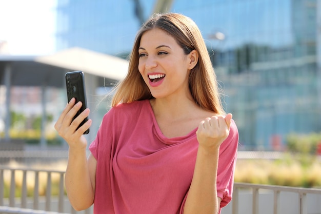 Mujer leyendo buenas noticias online en smartphone en la calle